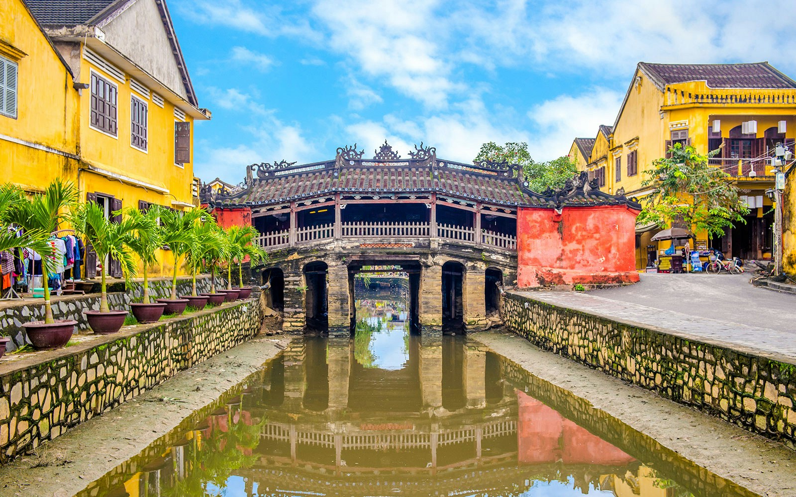 Japanese Bridge in Hoi An with yellow buildings and water reflection.
