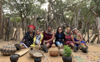 Group sitting in traditional attire at cultural village near Durban.