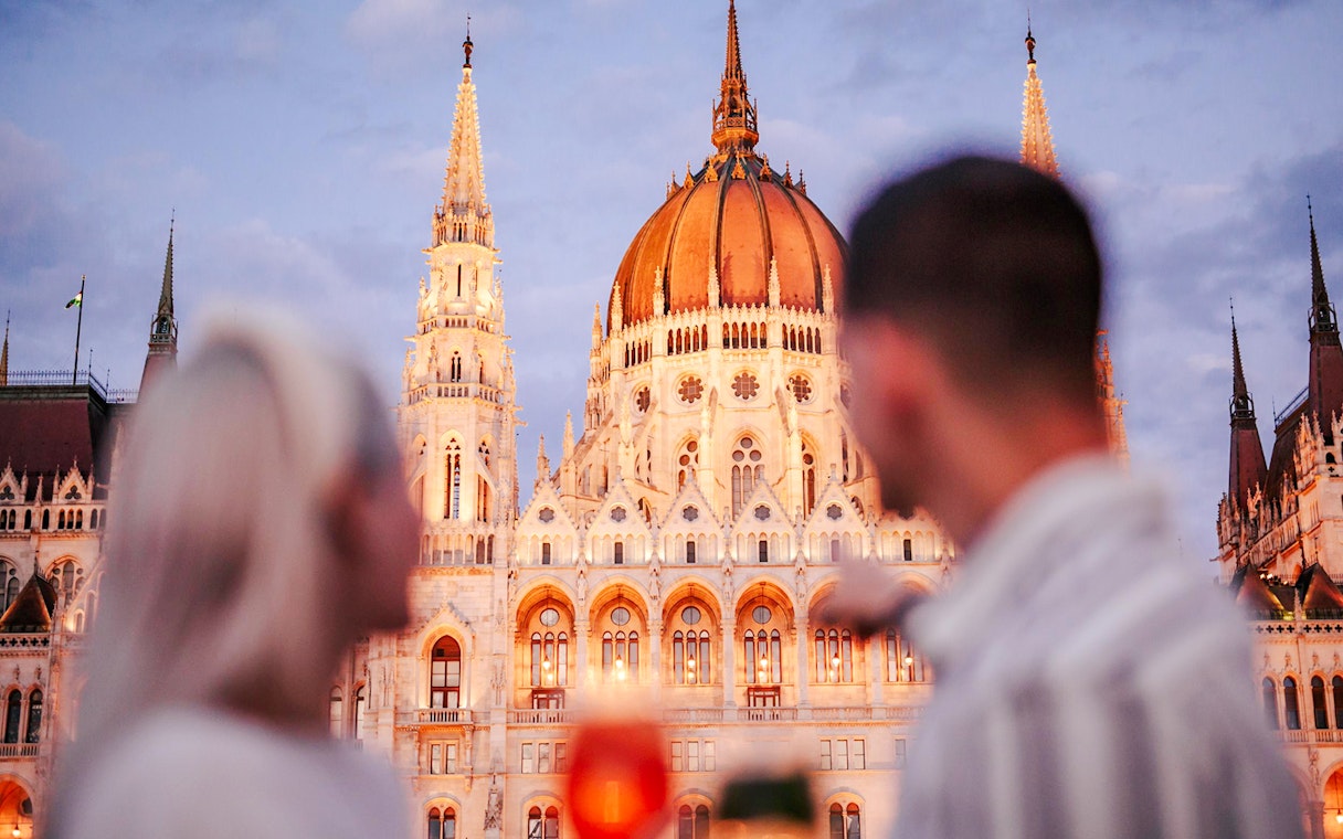 Couple viewing Budapest Parliament from Danube River nighttime cruise.
