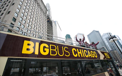 Open-top bus with tourists on Chicago Hop-On-Hop-Off Tour, skyscrapers in background.