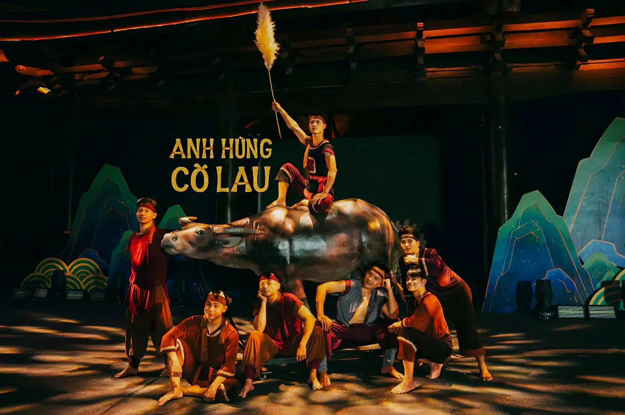 Performers in traditional attire with a buffalo statue at Anh Hùng Cờ Lau Show, Hoa Lư, Ninh Binh.