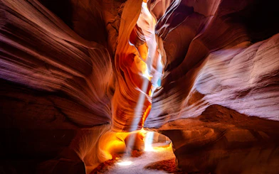 Antelope Canyon's sandstone walls with light beams, part of a small group tour.