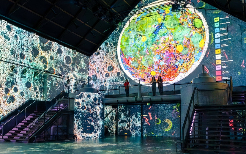 Guests viewing lunar art projections at Moonwalkers Exhibition, Fabrique des Lumières, Amsterdam.