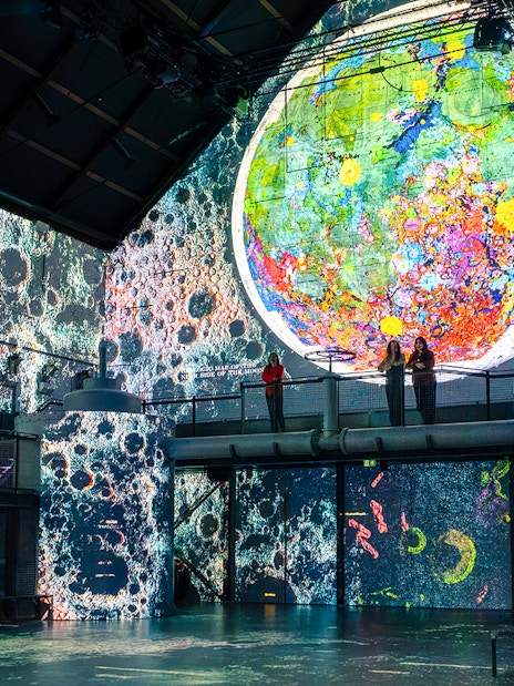 Guests viewing lunar art projections at Moonwalkers Exhibition, Fabrique des Lumières, Amsterdam.