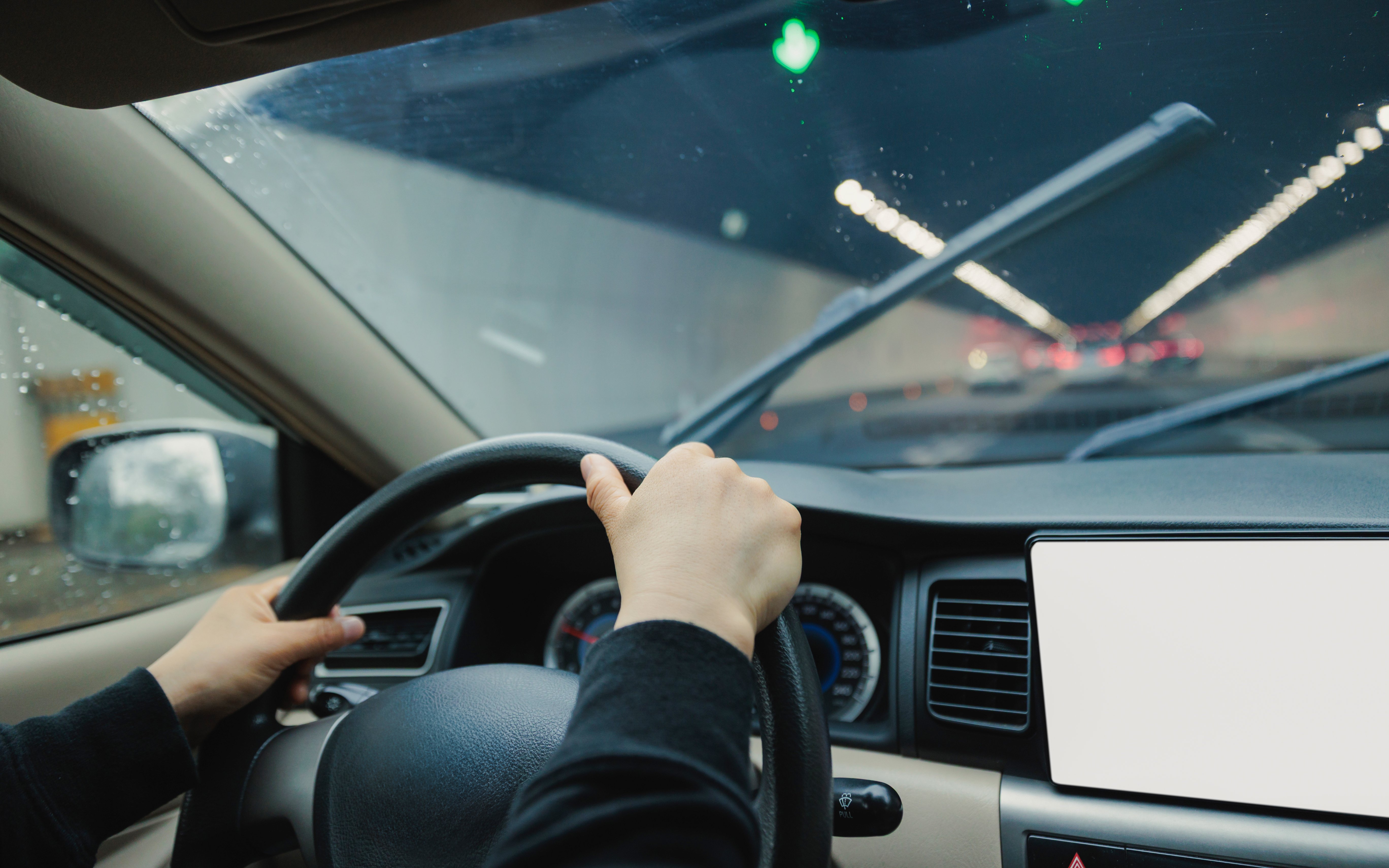Driving through a tunnel with windshield wipers on, view from inside the car.