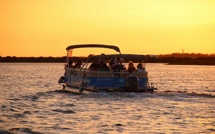 Boat with passengers on Ria Formosa during sunset tour.