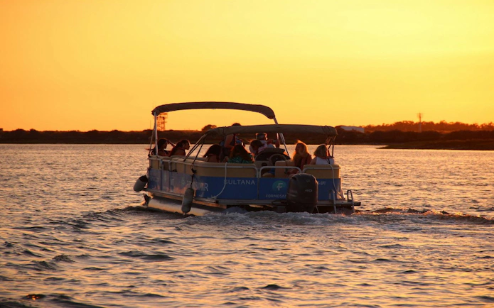 Boat with passengers on Ria Formosa during sunset tour.
