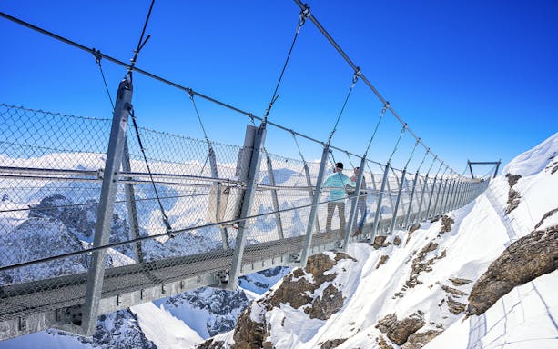 Titlis Cliff Walk suspension bridge over snowy peaks in Engelberg, Switzerland.
