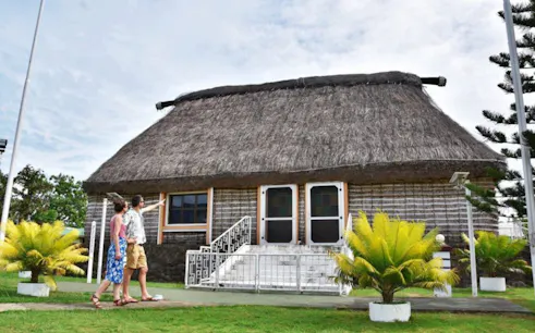 Visitors exploring a traditional thatched-roof building in Nadi village, Fiji.