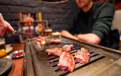 Grilling A5 Wagyu beef on a tabletop grill during Tokyo Omakase Sushi & Foodie Tour in Shinjuku.