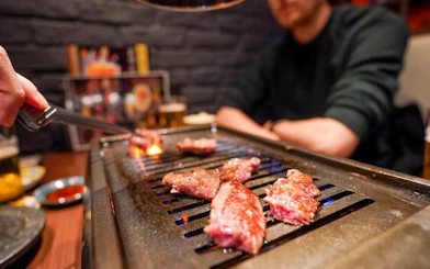 Grilling A5 Wagyu beef on a tabletop grill during Tokyo Omakase Sushi & Foodie Tour in Shinjuku.