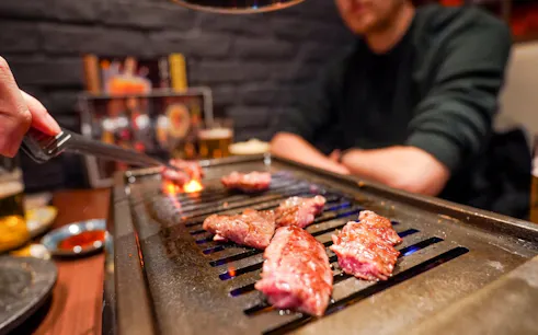 Grilling A5 Wagyu beef on a tabletop grill during Tokyo Omakase Sushi & Foodie Tour in Shinjuku.