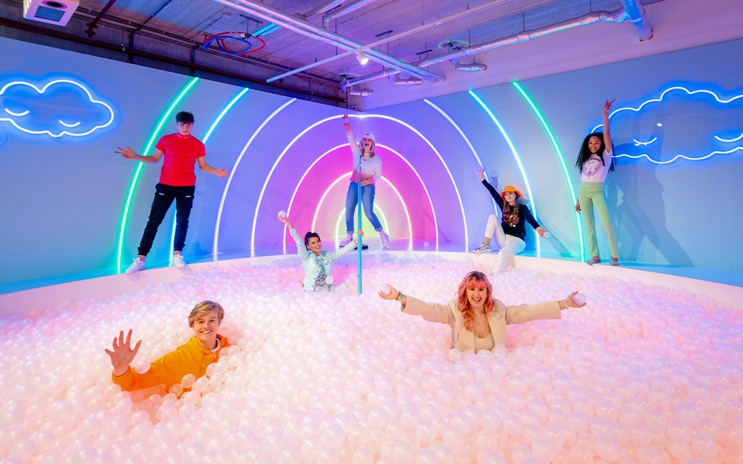 Visitors enjoying The Pool Upside Down Amsterdam with neon lights and ball pit.