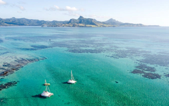 Catamarans sailing to Ile aux Cerfs from Pointe Jerome, Mauritius, with scenic mountain backdrop.