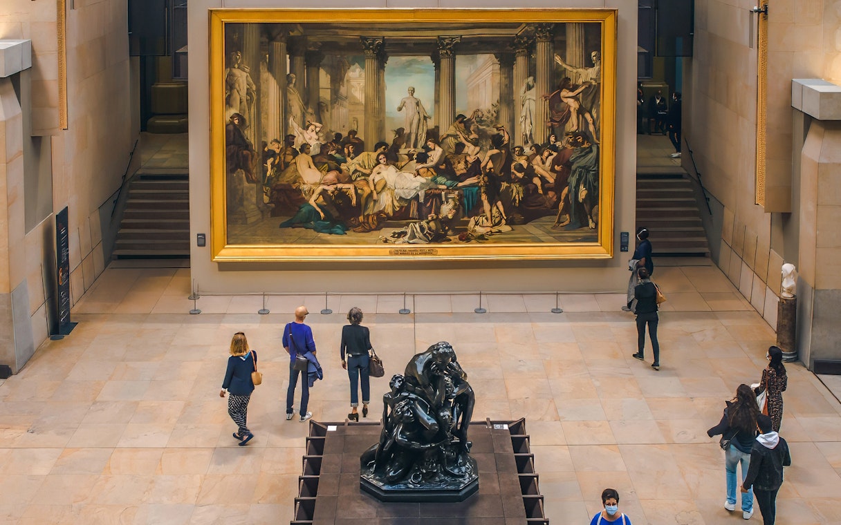 Visitors with guide viewing artwork at d’Orsay Museum, Paris.
