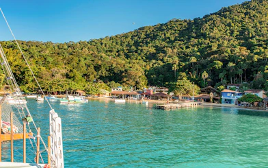 Boats docked at Freguesia de Santana beach, Ilha Grande, with lush forest backdrop.