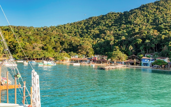 Boats docked at Freguesia de Santana beach, Ilha Grande, with lush forest backdrop.
