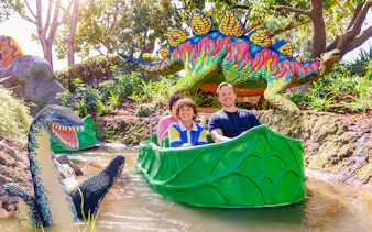 Family enjoying a boat ride past LEGO dinosaur sculptures at LEGOLAND® California.