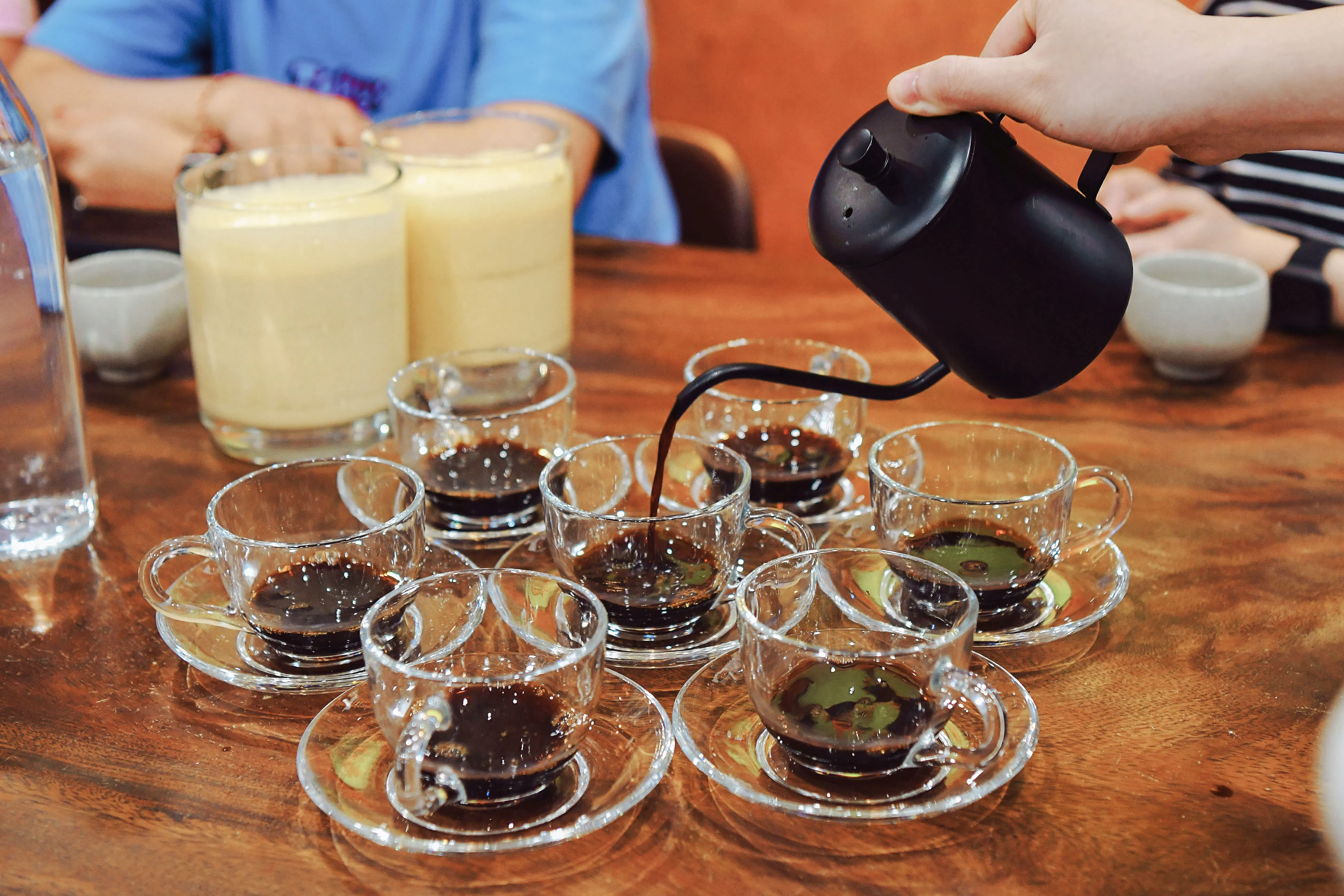 Pouring coffee into cups at Hanoi Coffee Workshop, featuring egg and coconut coffee.