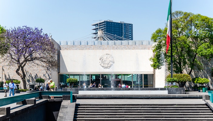 Main entrance of Anthropology Museum, Mexico City, featuring iconic architectural design and visitors exploring.