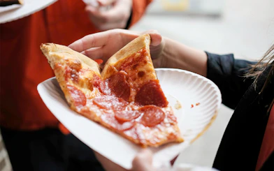 Slices of pepperoni pizza on a paper plate in New York street.