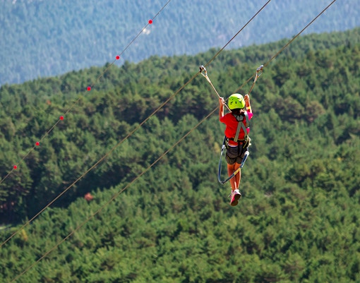Naturland Outdoor Adventure Park Andorra zipline through lush forest landscape.
