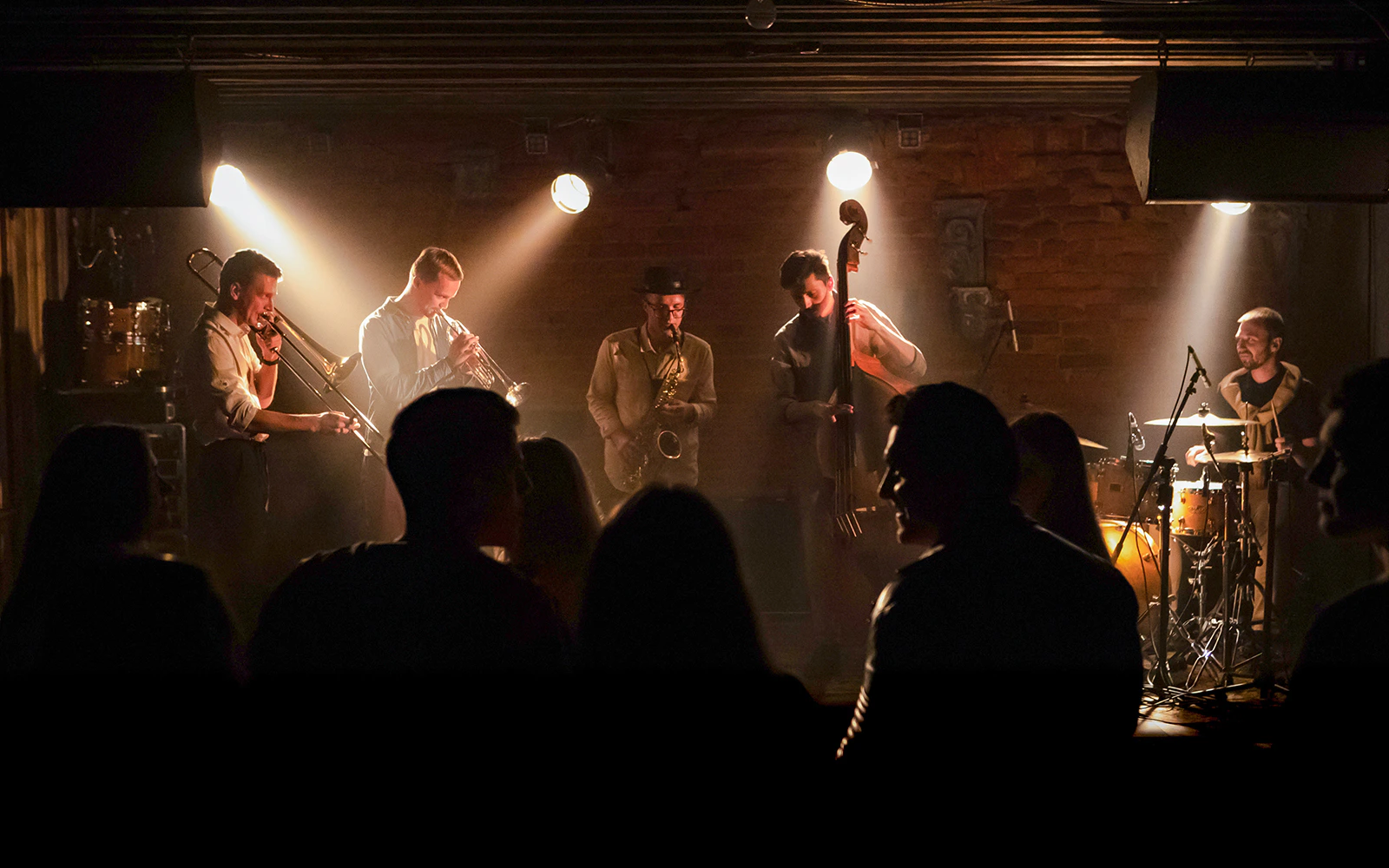 Musicians performing modern jazz on stage with audience dancing.