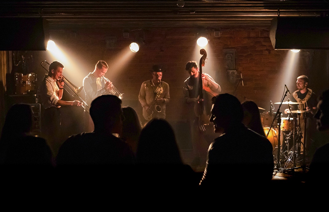 Musicians performing modern jazz on stage with audience dancing.