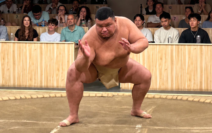 Sumo wrestler performing in front of an audience at a Kyoto live sumo show.
