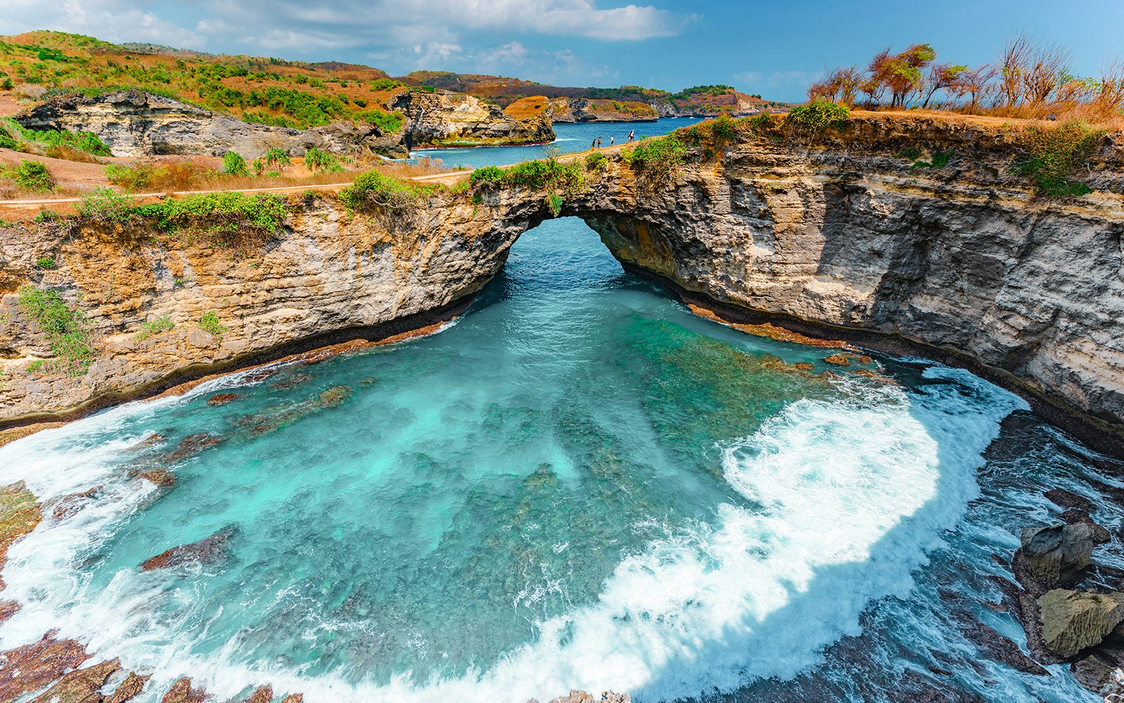 Stunning view of the natural rock arch at Broken Beach, Nusa Penida, with turquoise waters and dramatic cliffs, a unique day trip destination in Bali