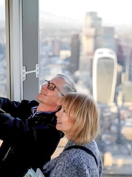 Couple taking a selfie at a London skyscraper with cityscape view.
