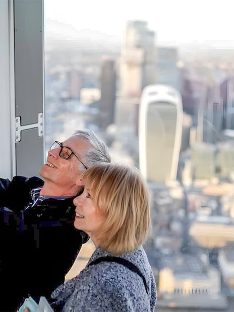Couple taking a selfie at a London skyscraper with cityscape view.
