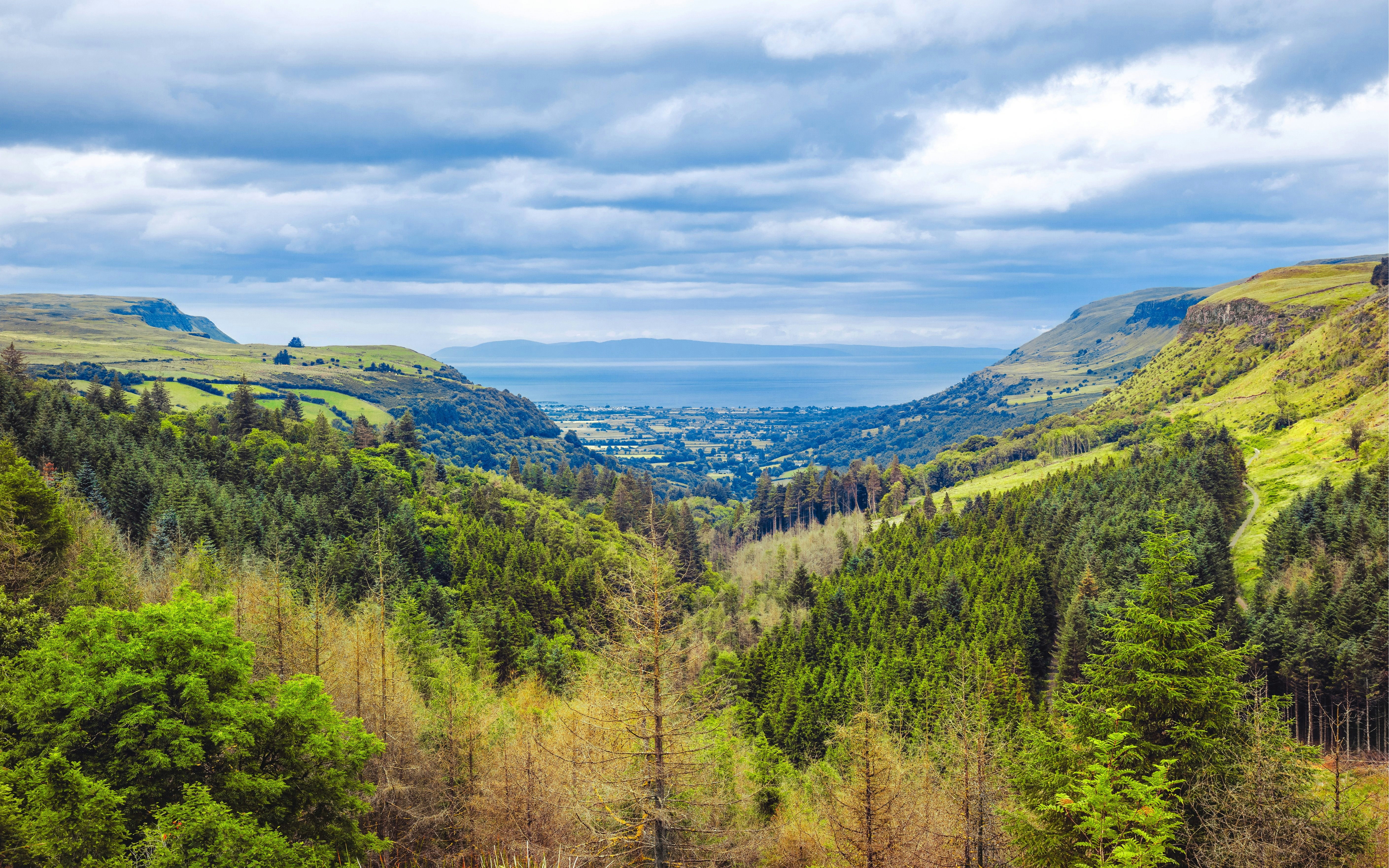Glens of Antrim landscape with lush greenery and distant sea view, County Antrim, Northern Ireland.