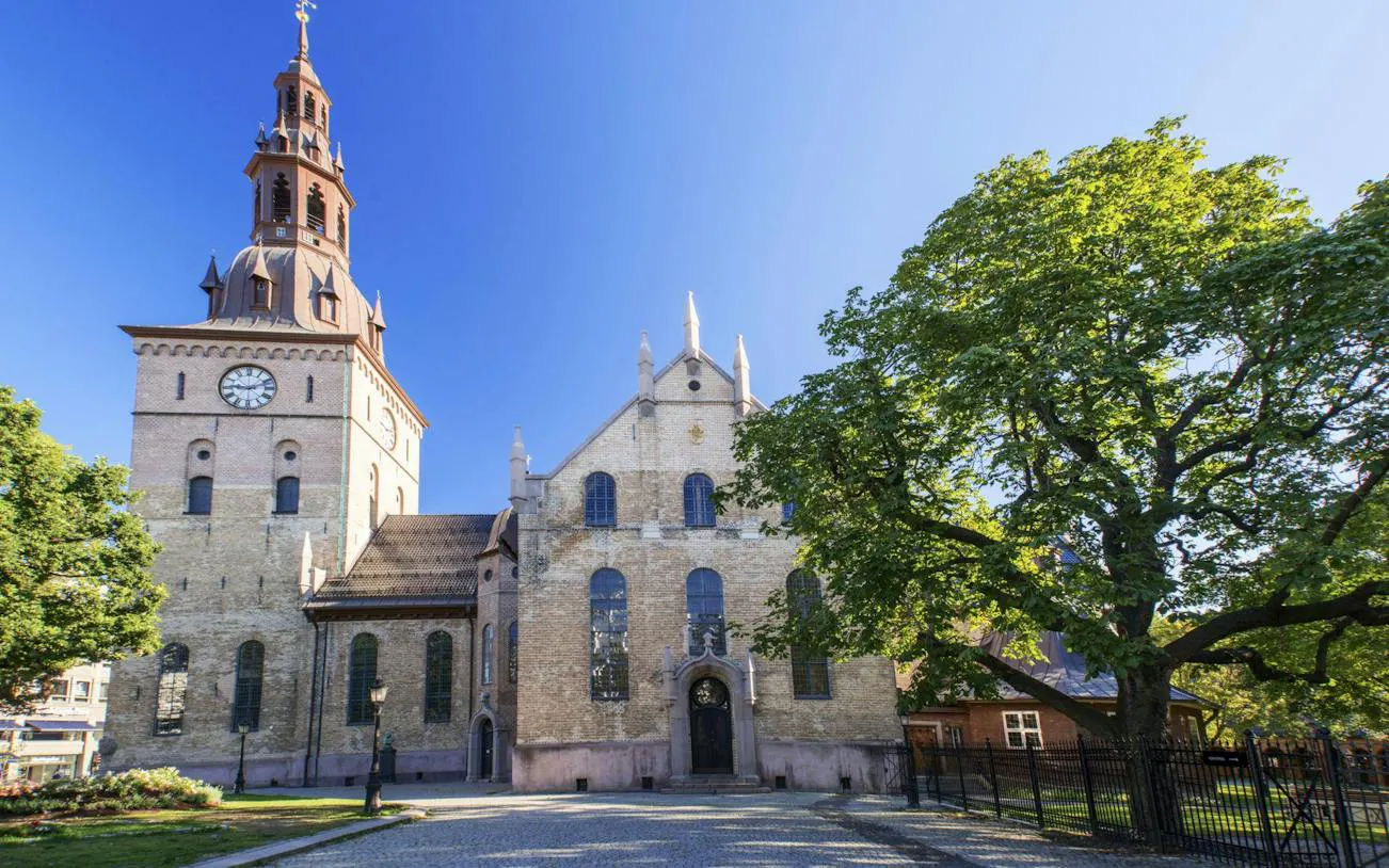 Oslo Cathedral with clock tower and trees on a sunny day, Oslo Walking Tour.