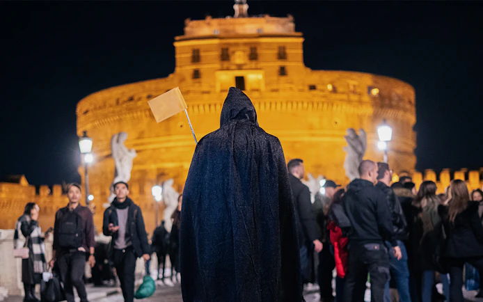 Cloaked guide leading a haunted ghost tour near Castel Sant'Angelo, Rome.