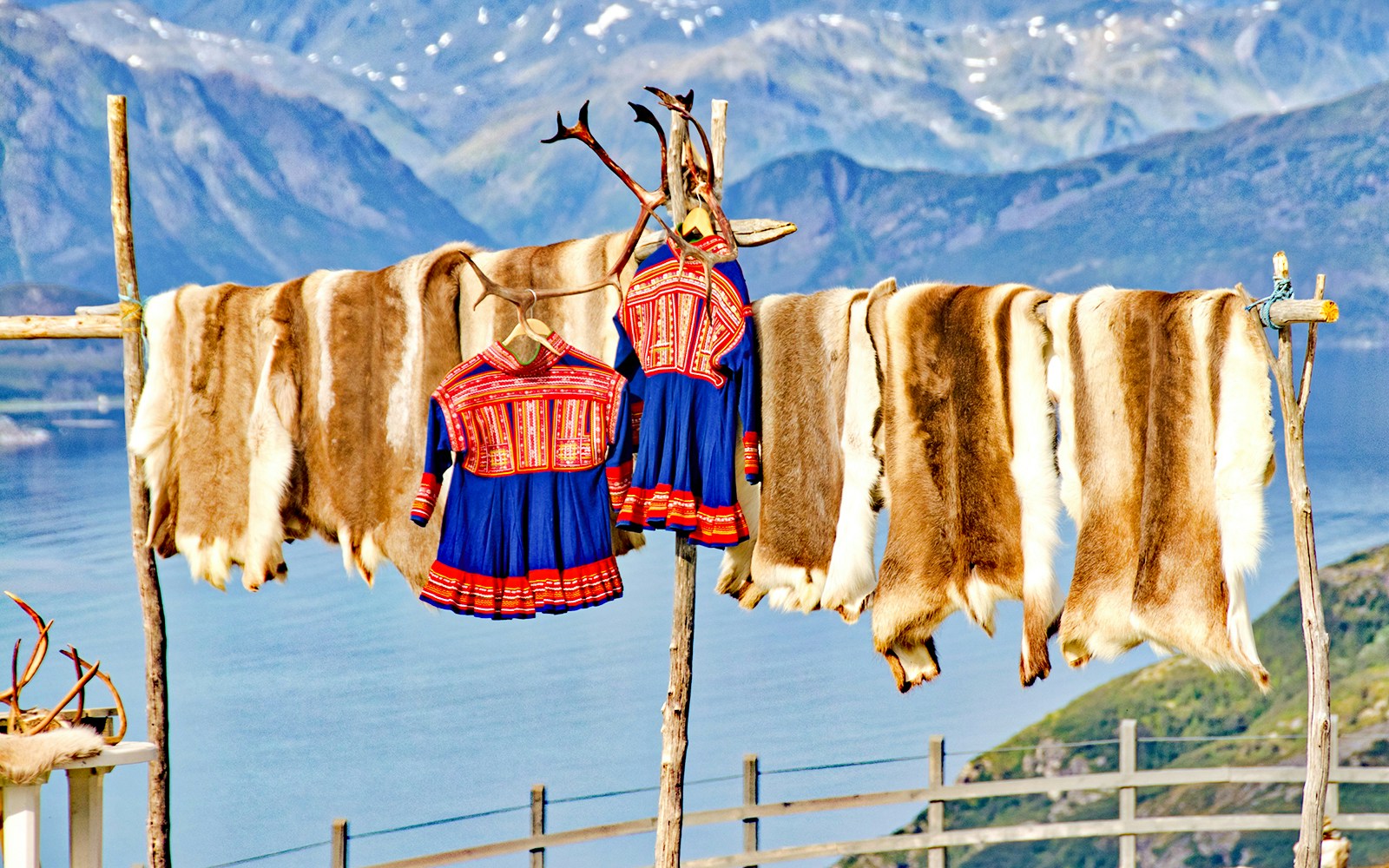 Traditional Sámi clothing and reindeer hides drying in Lapland.