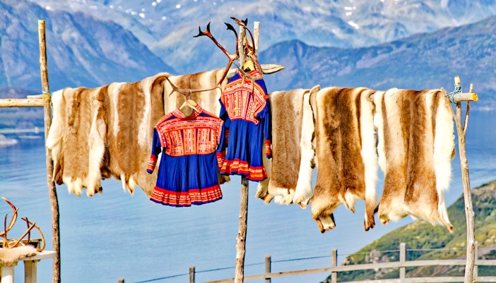 Traditional Sámi clothing and reindeer hides drying in Lapland.
