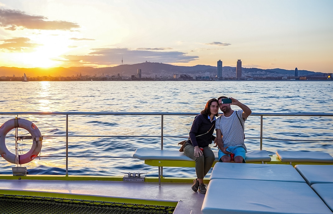 Tourists enjoying a Catamaran Cruise in Barcelona with a view of the city skyline