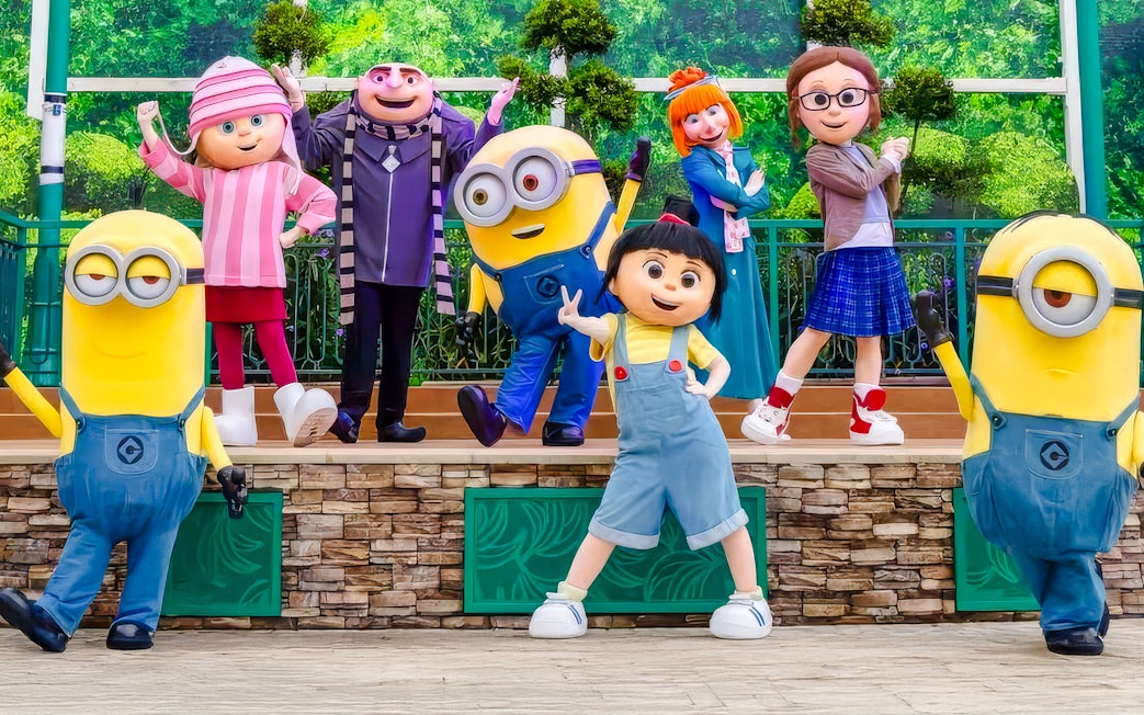 Gru, Lucy, the girls, and Minions posing together for a family photo at a theme park.
