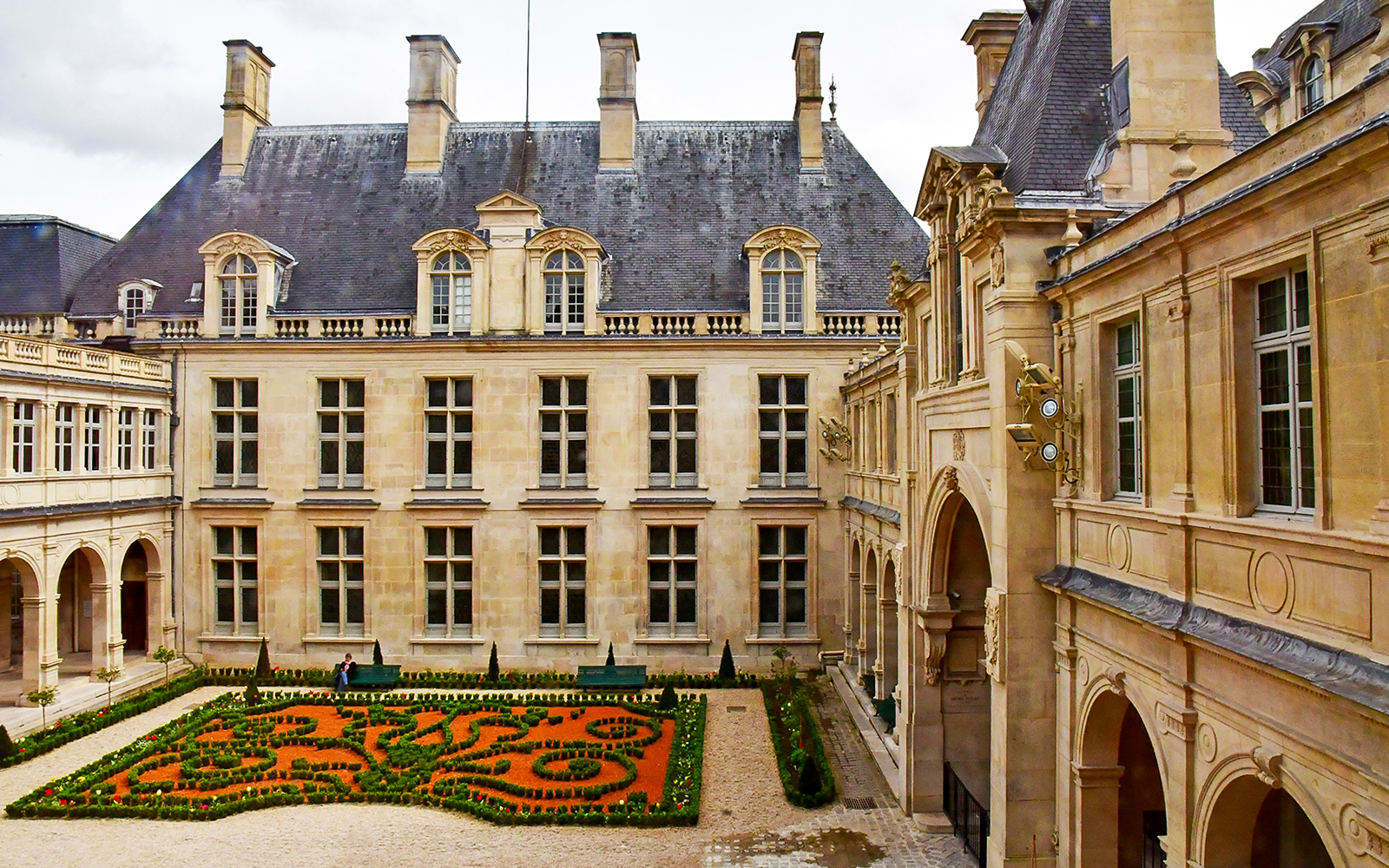 Courtyard of Musee Carnavalet in Paris with manicured garden and historic architecture.