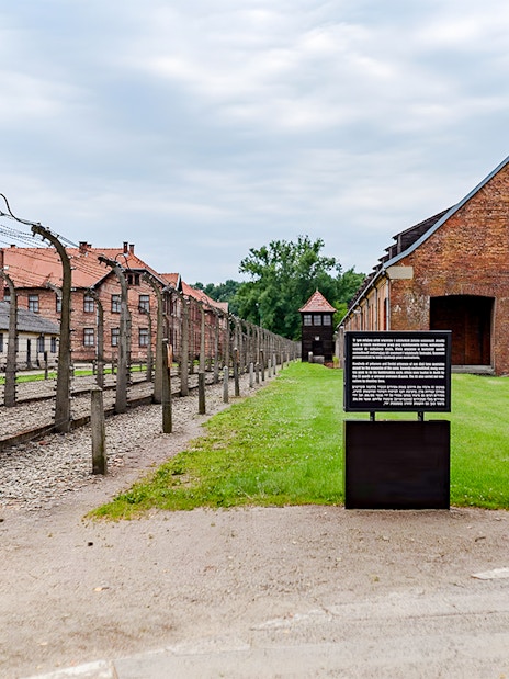 Auschwitz I barrack with barbed wire fence and informational sign, Auschwitz Birkenau.