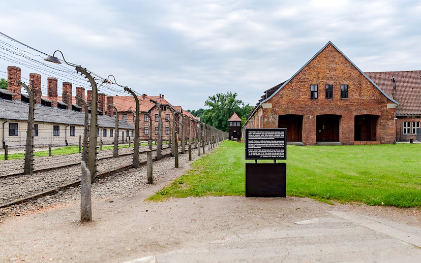 Auschwitz I barrack with barbed wire fence and informational sign, Auschwitz Birkenau.