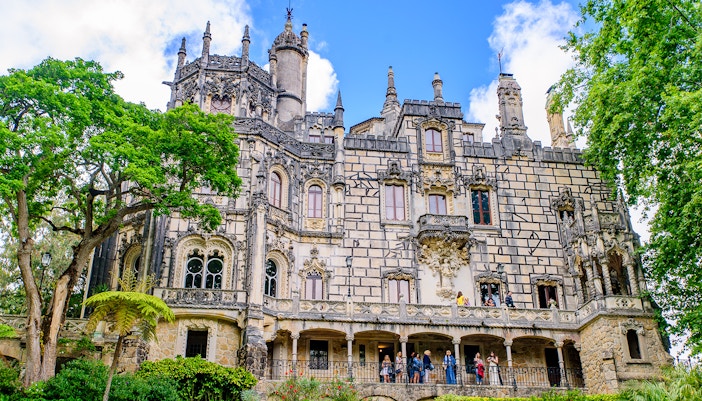 Quinta da Regaleira palace and gardens with tourists exploring the intricate architecture in Sintra, Portugal.