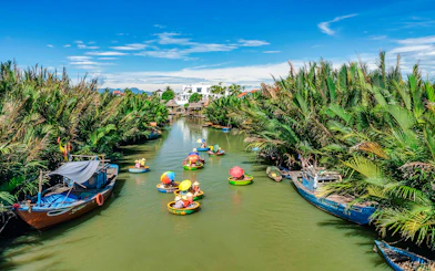 People in round bamboo boats on a river in Cam Thanh Village, surrounded by lush greenery.