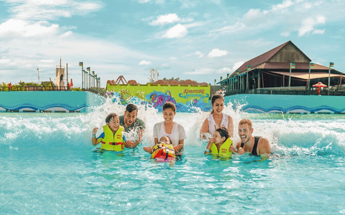 Family enjoying wave pool at Adventure Waterpark Desaru Coast.