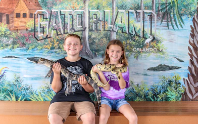 Children holding reptiles at Gatorland, Orlando backdrop.