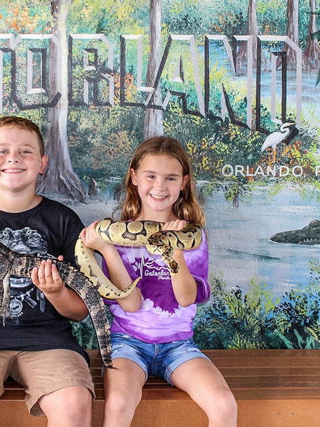 Children holding reptiles at Gatorland, Orlando backdrop.