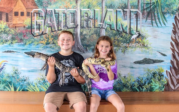 Children holding reptiles at Gatorland, Orlando backdrop.