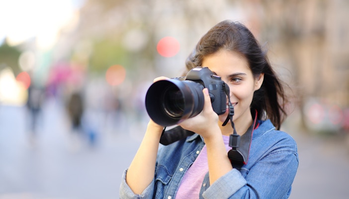 Woman photographing Eiffel Tower in Paris with DSLR camera.