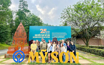 Group at My Son Sanctuary entrance, Vietnam, with temple replica and anniversary sign.